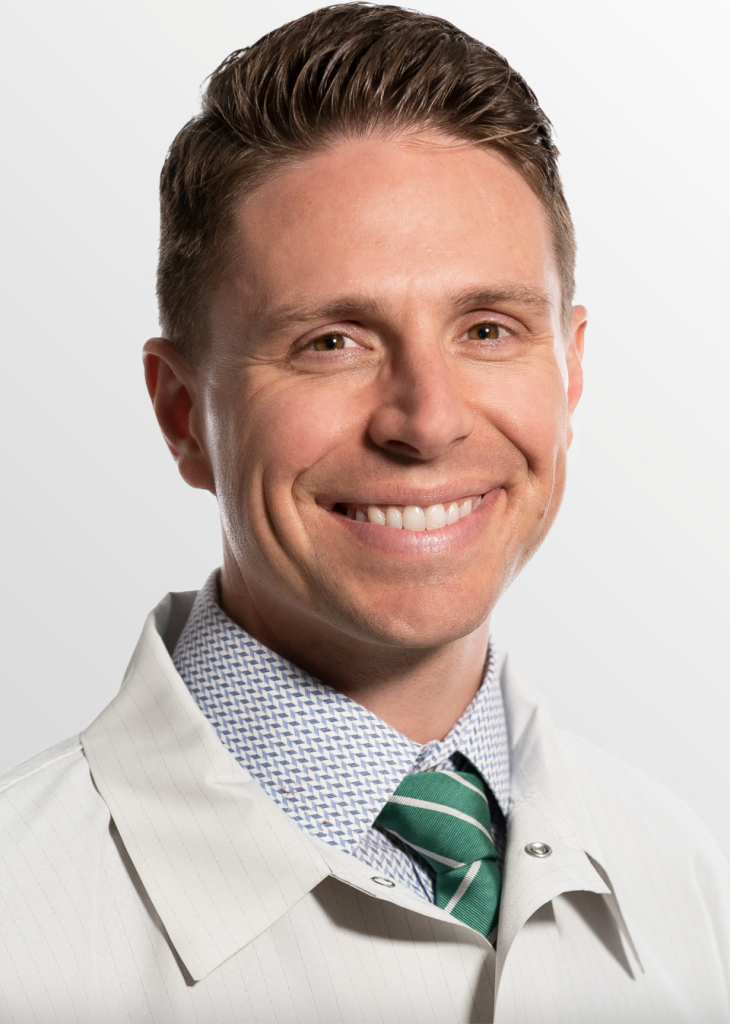 Smiling dentist in a white coat and patterned shirt, representing the professional team at Ivory Dental Implant Center, emphasizing expertise in dental care and implant dentistry.