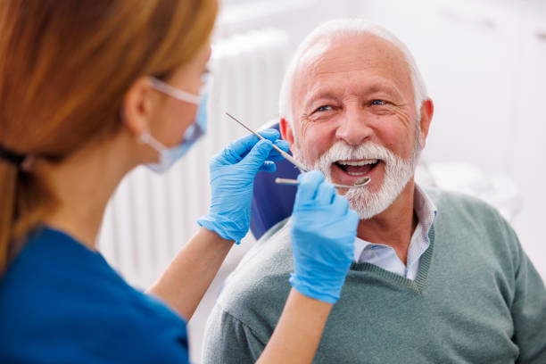Smiling elderly man in dental chair receiving care from a dentist, highlighting a comfortable and relaxed experience during sedation dentistry.