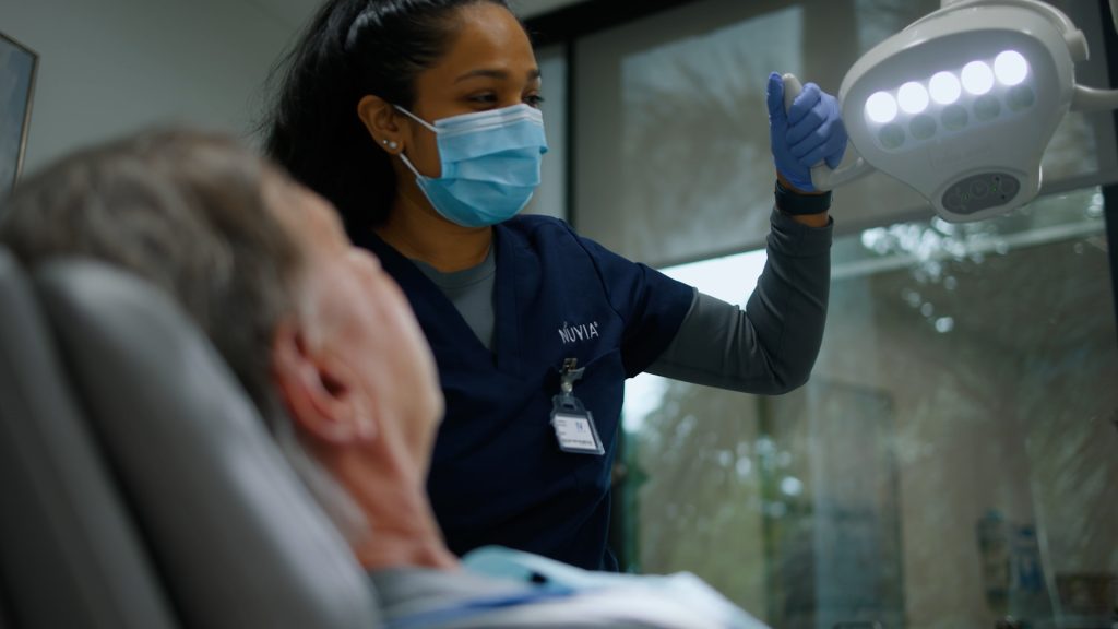 Dental nurse adjusting overhead light for patient receiving sedation dentistry at Ivory Dental Implant Center.