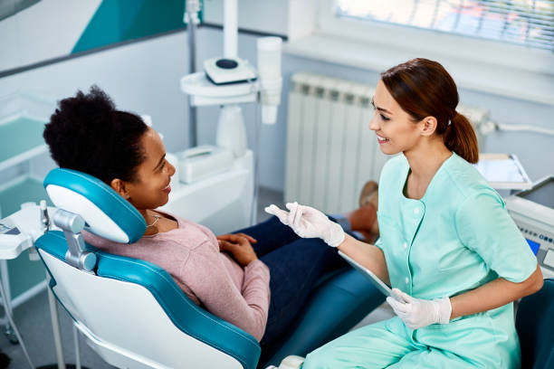Dental professional consulting with a patient in a dental office, discussing dental implants and oral health care.