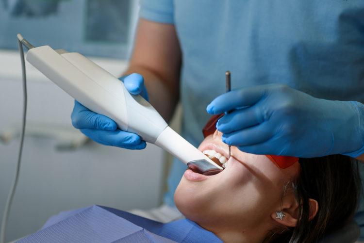 Dental professional using an intraoral scanner on a patient receiving All-on-4 dental implants, highlighting advanced technology in full mouth restoration.